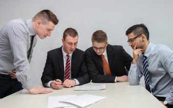 four men looking to the paper on table