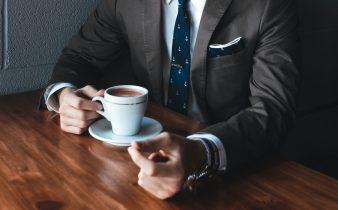 man holding cup filled with coffee on table